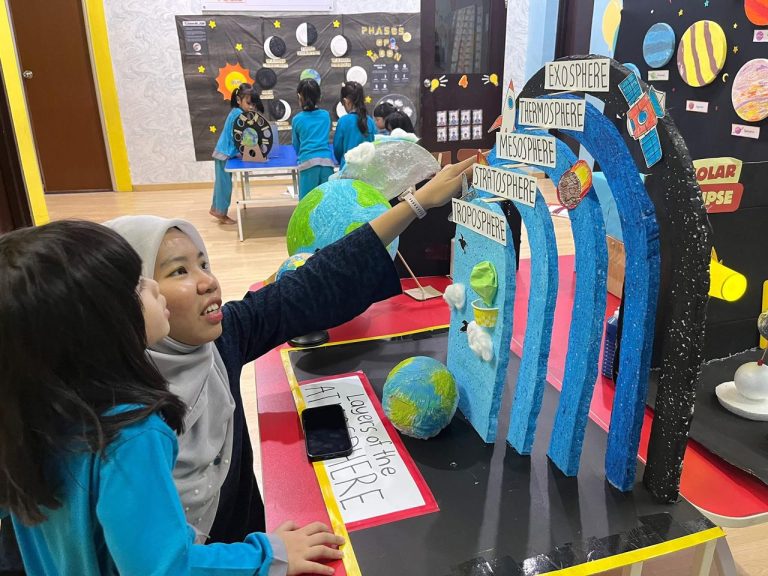 A teacher guiding a child at a Space World display at Excel Kids
