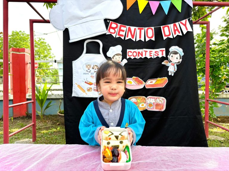 A child displaying a decorated bento meal at Excel Kids